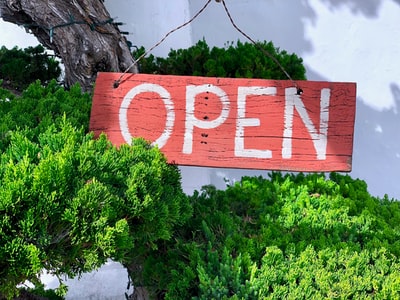 Green, brown and white open sign on the grass
